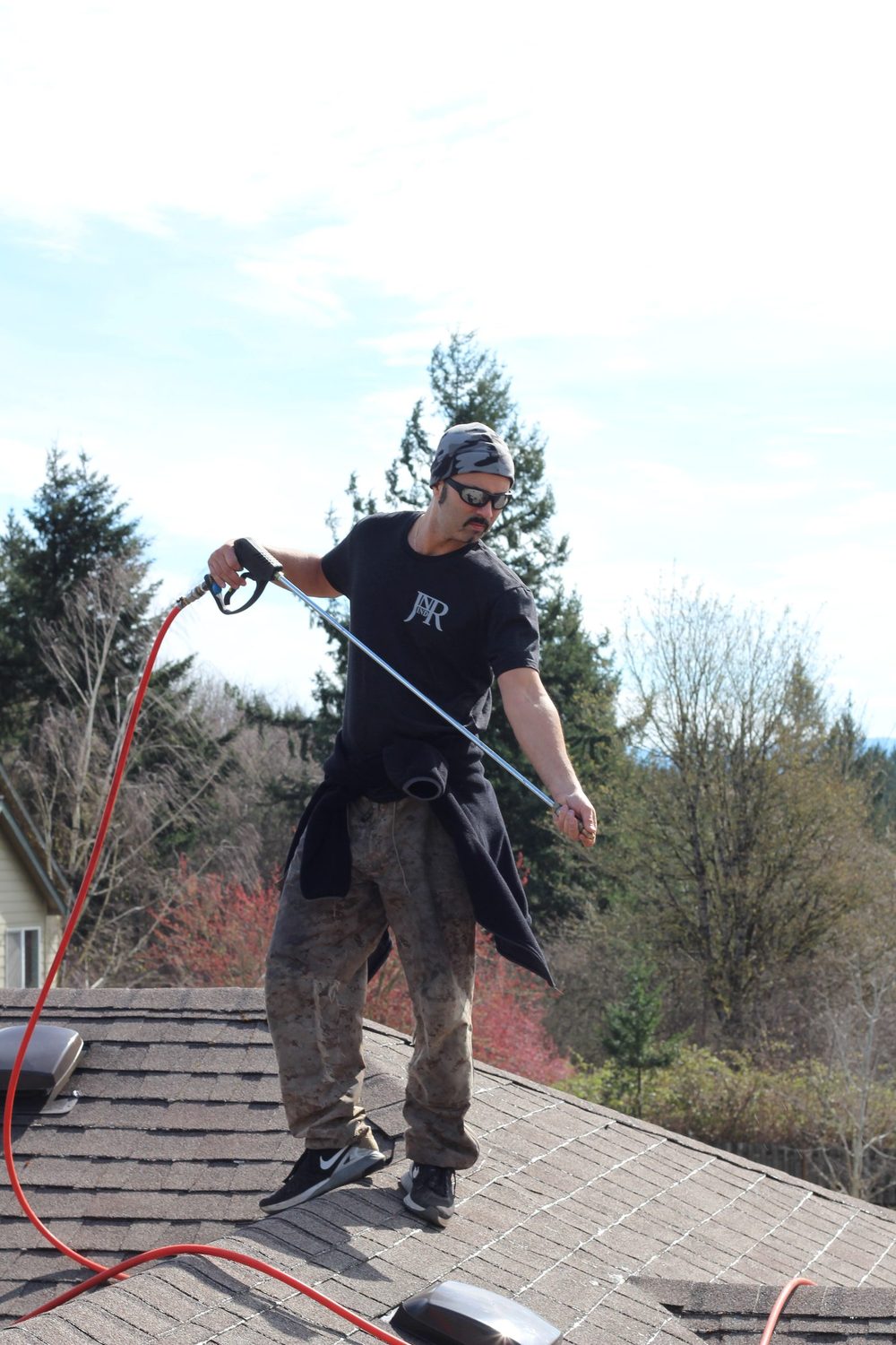 Jesse working on a Portland-area roof during a moss treatment job